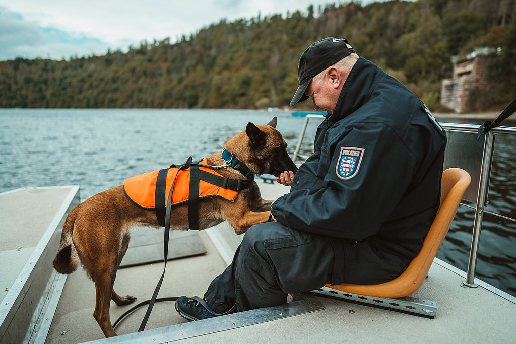 Polizeihund mit seinem Diensthundführer auf einem Boot im Wasser