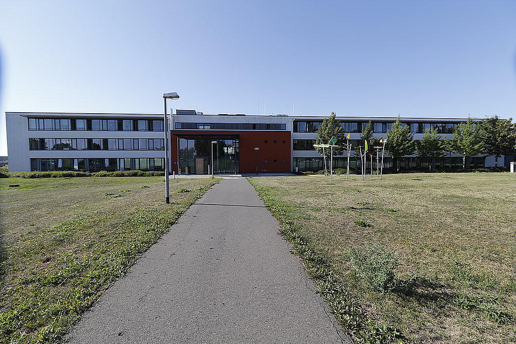 Dienstgebäude der Zentralen Bußgeldstelle mit einem Weg und einer grünen Wiese davor.