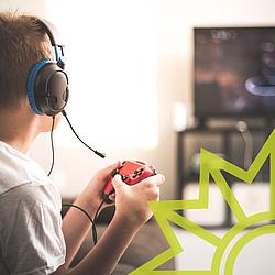 Teenager beim Onlinespiel Junge mit einem Telefonkopfhörer und einem Sprechset sowie einem Steuergerät in der Hand vor einem Fernsehen.