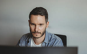 Sachbearbeiter Dennis B. an seinem Arbeitsplatz vor dem Computer