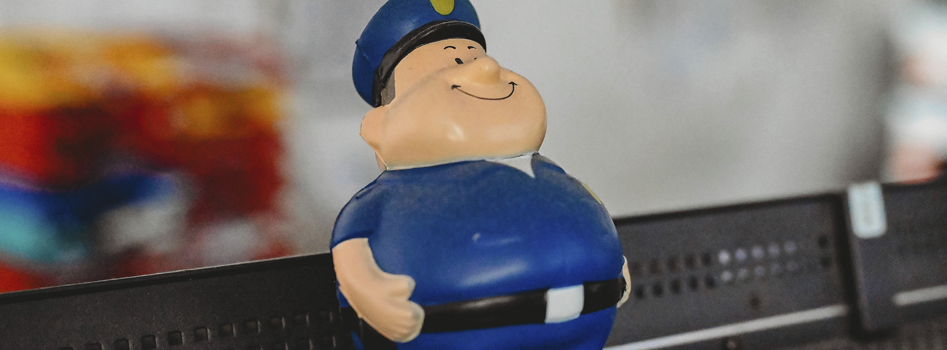 Ein Stressball in Form eines Polizisten seht auf der Oberkante eines Bildschirms. Nahaufnahme