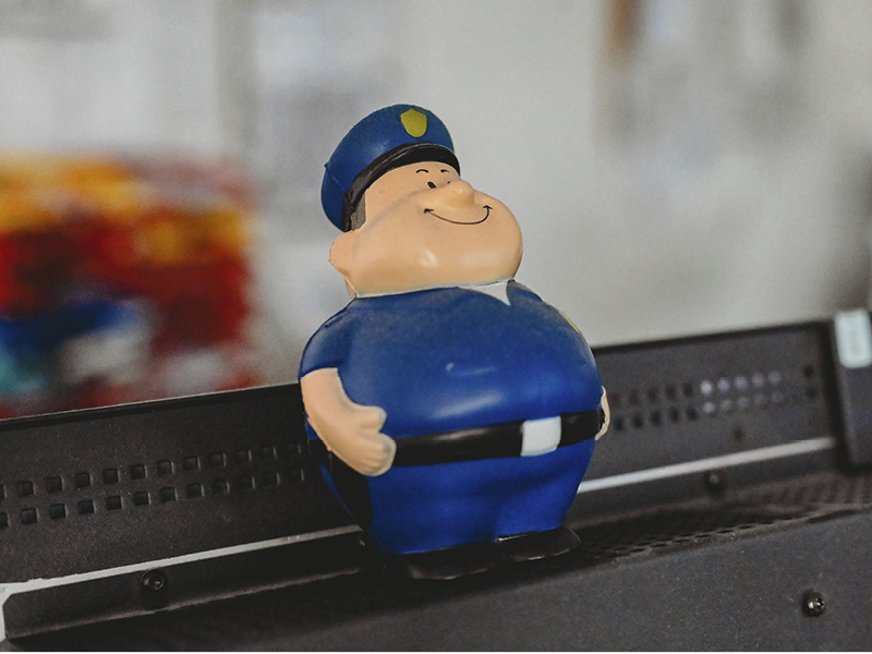 Nahaufnahme eines Antistressballs in Form eines Polizisten, der auf einem Bilderschirm stehtonitor.