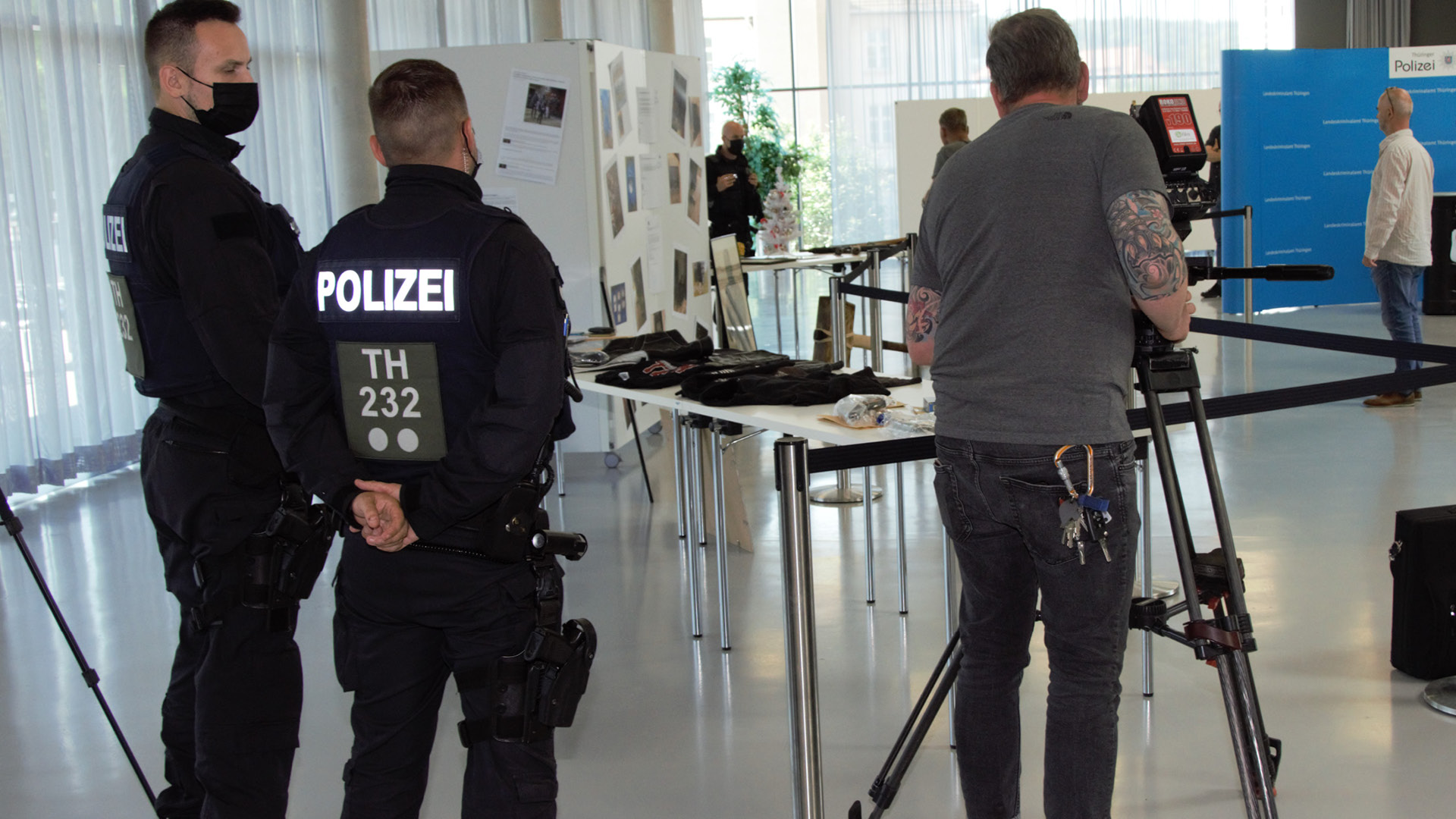 2 Polizisten und 1 Kameramann während der Pressekonferenz